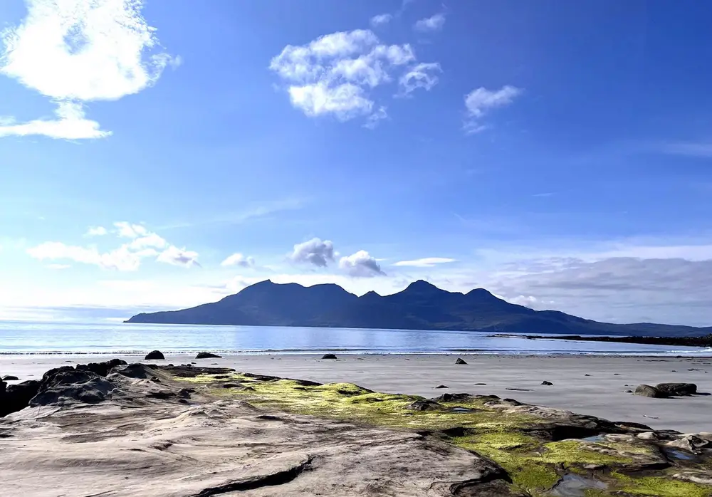 The Isle of Eigg seen across a bright, empty beach