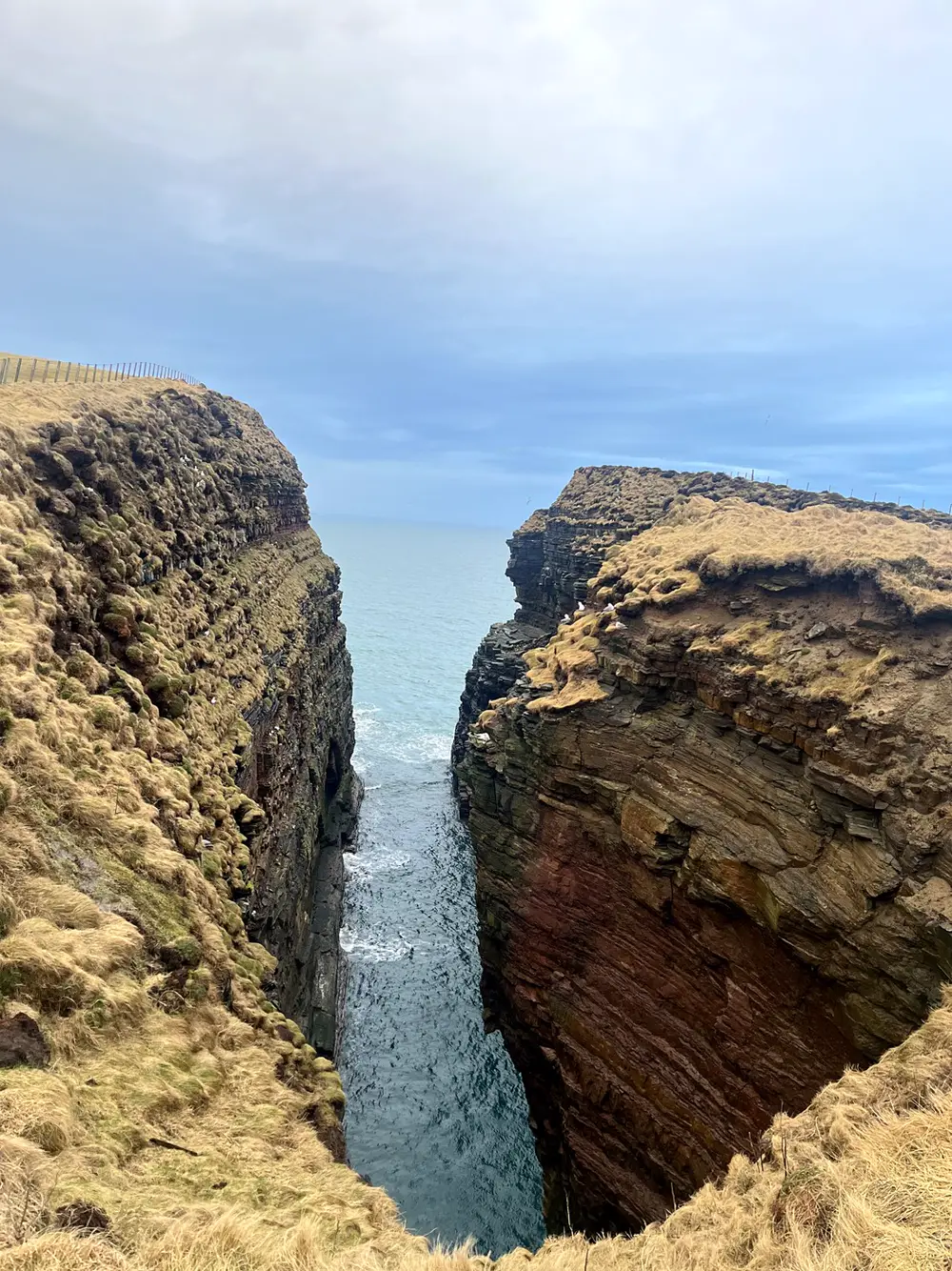 A narrow chasm between two sandstone cliffs, opening to the sea
